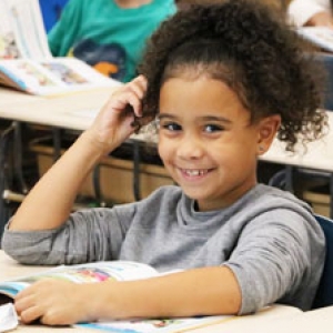 student smiling while sitting at her desk